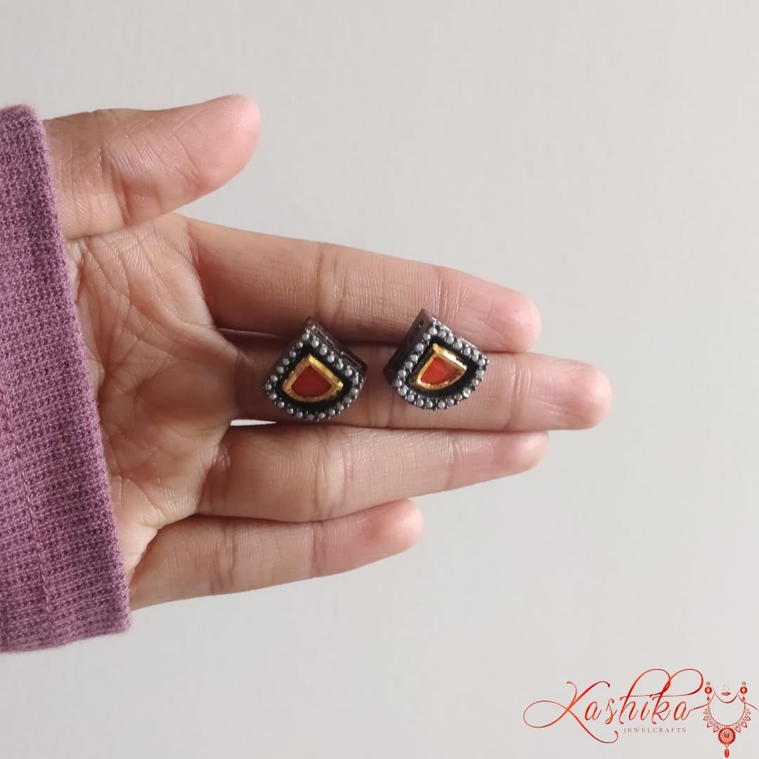 Oxidised stud earrings with teardrop shaped red gemstone bordered by gold and silver detailing